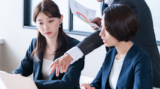 資料を手にオフィスで相談する女性社員たち